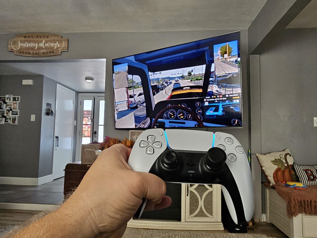 PlayStation 4 controller next to computer screen displaying Euro Truck Simulator 2 main menu