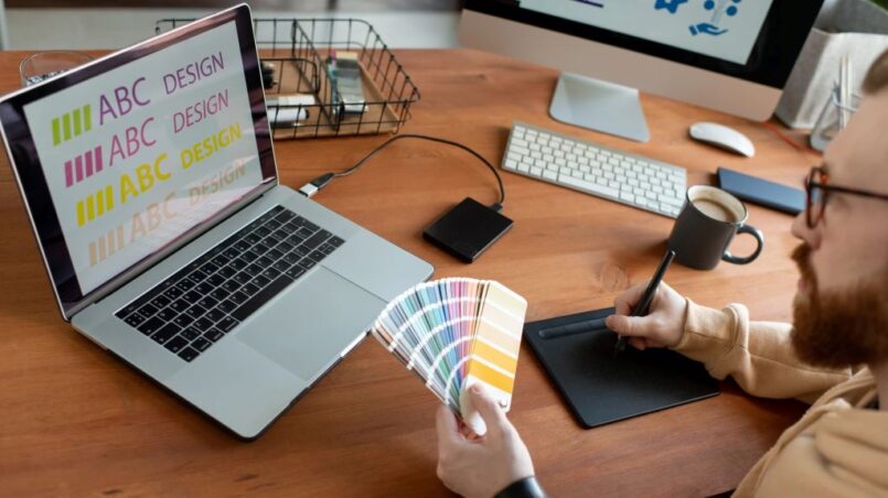 Designer reviewing font licensing options on computer screen with client documents and typography samples visible on desk