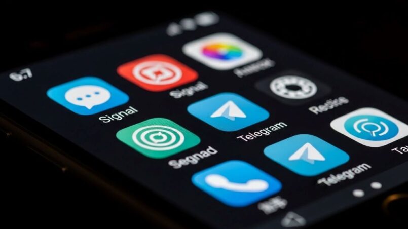 Smartphone screen displaying multiple secure messaging app icons including Signal and Telegram on dark background