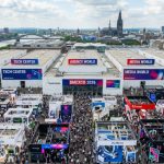 Aerial view of the packed Koelnmesse exhibition halls during DMEXCO 2026 in Cologne, Germany, with thousands of digital marketing professionals exploring exhibitor stands across the five themed DMEXCO Worlds