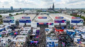 Aerial view of the packed Koelnmesse exhibition halls during DMEXCO 2026 in Cologne, Germany, with thousands of digital marketing professionals exploring exhibitor stands across the five themed DMEXCO Worlds