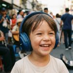Child wearing safe volume limiting noise cancelling headphones in noisy airport.